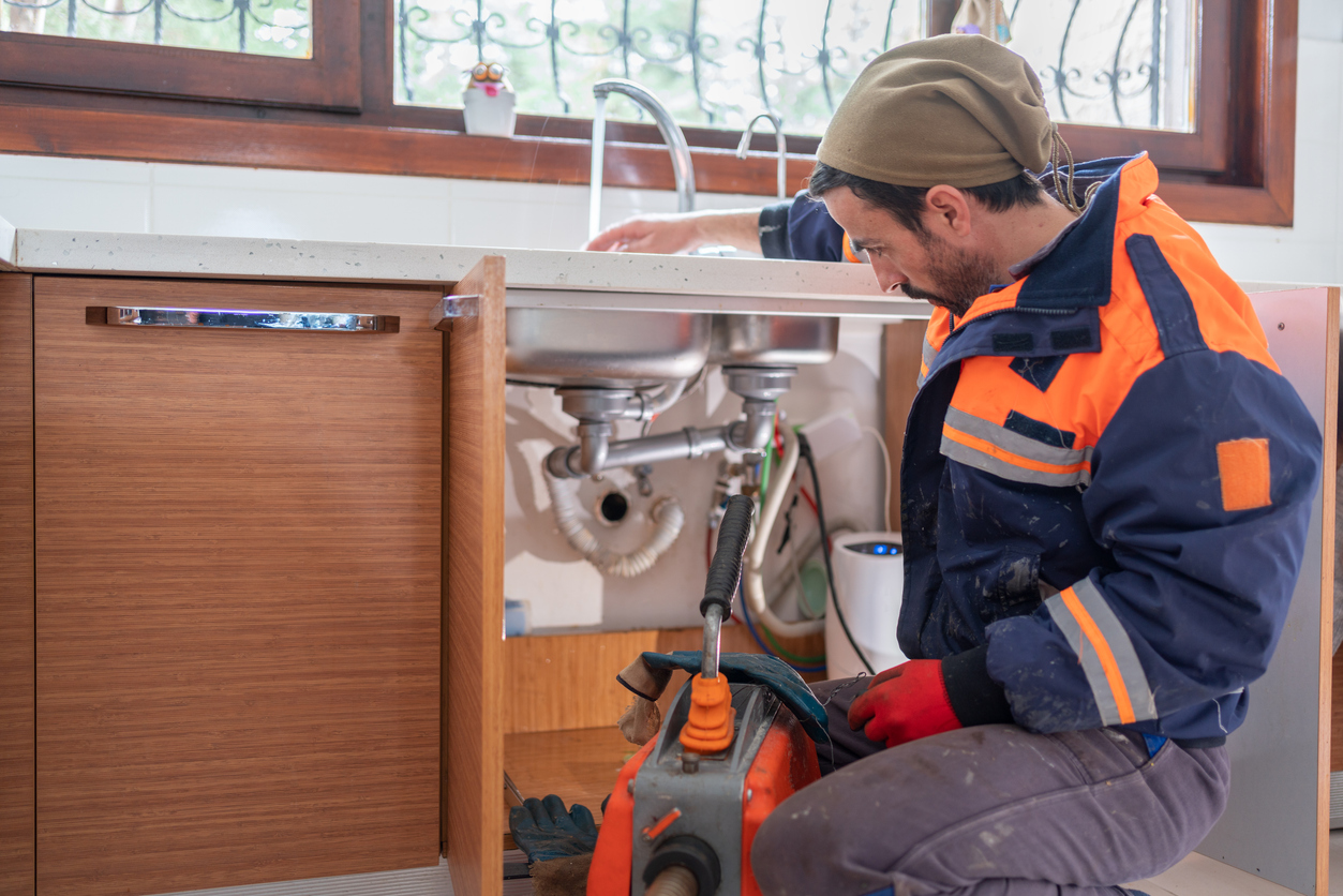 Cleaning a garbage disposal professionally - A male plumber checking a home's garbage disposal.