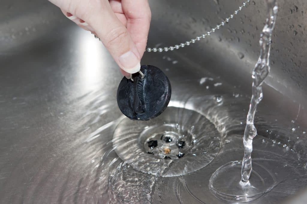 lightly clogged sink with a stopper and running water