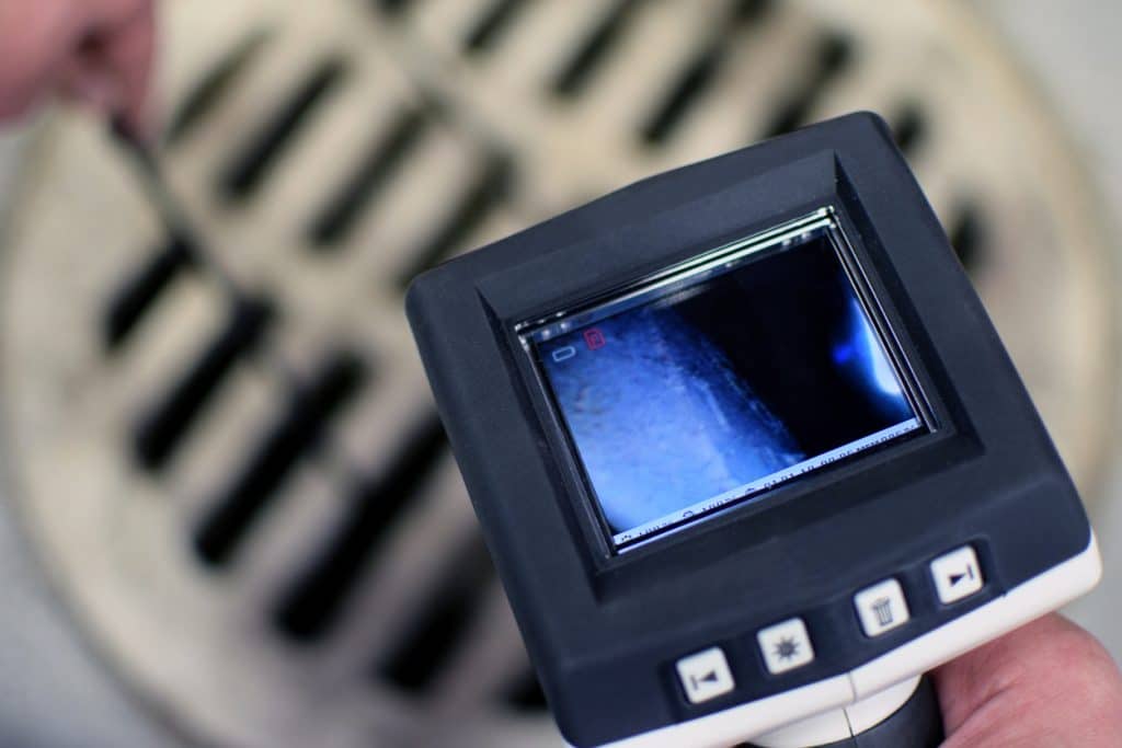 Plumber using a high-tech camera to detect problems in the sewer line - sewer video inspection services.