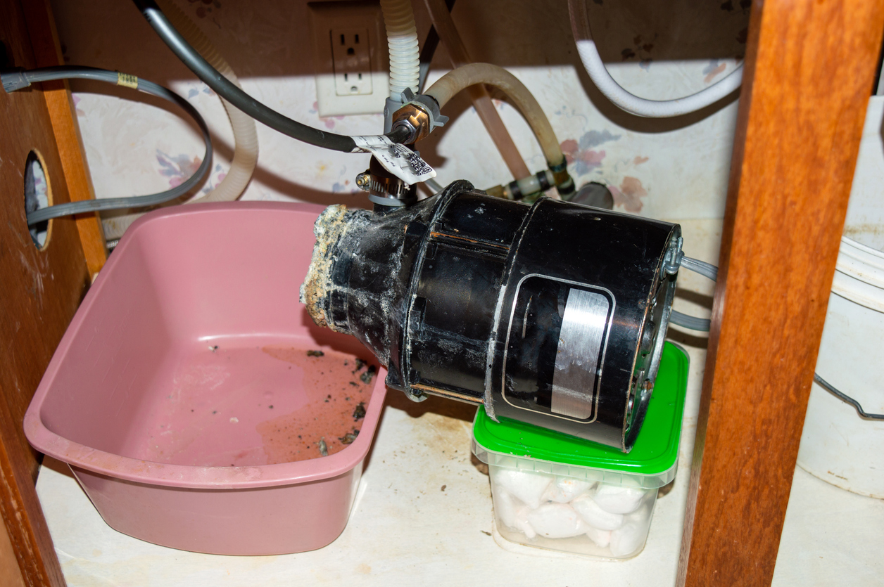 Cleaning a garbage disposal - A clogged and eroded garbage disposal located under the sink.