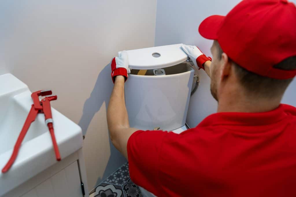 Expert male plumber fixing a residential home's toilet system.